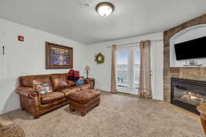 Carpeted living room featuring a textured ceiling and a fireplace