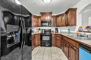 Kitchen with sink, light tile patterned floors, and black appliances