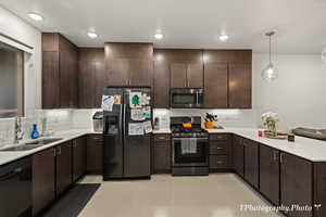 Kitchen featuring pendant lighting, sink, appliances with stainless steel finishes, tasteful backsplash, and dark brown cabinetry