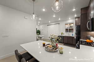 Kitchen featuring dark brown cabinetry, a kitchen bar, sink, appliances with stainless steel finishes, and pendant lighting