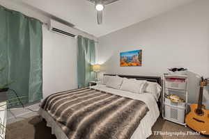 Carpeted bedroom featuring a wall unit AC and ceiling fan