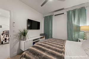 Carpeted bedroom with lofted ceiling, an AC wall unit, and ceiling fan