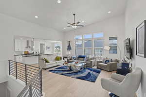 Living room with a high ceiling, ceiling fan, and light hardwood / wood-style flooring