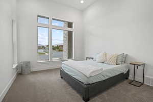 Carpeted bedroom with a high ceiling