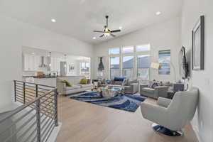 Living room with light hardwood / wood-style flooring, high vaulted ceiling, and ceiling fan