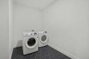 Washroom featuring separate washer and dryer and dark tile patterned flooring