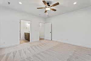 Unfurnished bedroom with ensuite bathroom, light carpet, and ceiling fan