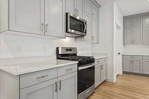 Kitchen featuring stainless steel appliances, gray cabinetry, and light hardwood / wood-style flooring