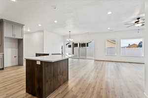 Kitchen featuring plenty of natural light, ceiling fan with notable chandelier, a kitchen island, and light hardwood / wood-style flooring