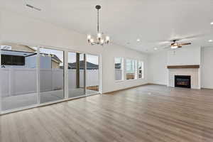 Unfurnished living room featuring hardwood / wood-style flooring, ceiling fan with notable chandelier, and a textured ceiling