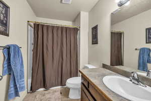 Full bathroom featuring shower / bath combination with curtain, vanity, and toilet