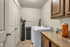 Laundry room with cabinets, light tile patterned floors, a textured ceiling, and washer and clothes dryer