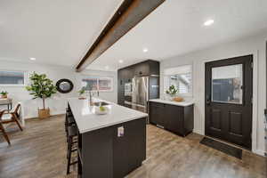 Kitchen featuring a breakfast bar, sink, appliances with stainless steel finishes, and an island with sink.