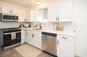 Kitchen featuring sink, dishwasher, white cabinetry, decorative backsplash, and range with gas cooktop