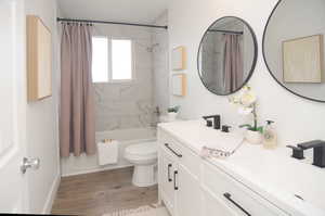 Full bathroom featuring hardwood / wood-style flooring, shower / tub combo with curtain, vanity, and toilet