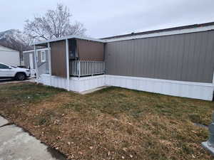 View of side of home with a mountain view and a lawn