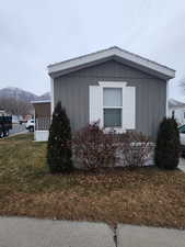 View of side of property with a mountain view and a lawn