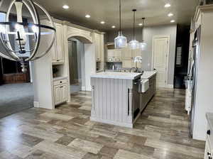 Kitchen with cream cabinets, a kitchen island with sink, and decorative light fixtures