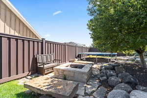 View of patio with a trampoline and an outdoor stone fire pit