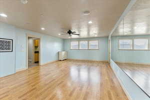 Dance studio featuring ceiling fan, a healthy amount of sunlight, a textured ceiling, and light wood-type flooring