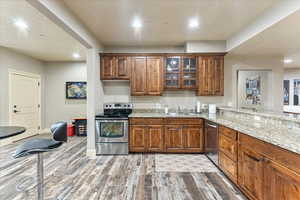 Kitchen featuring sink, hardwood / wood-style flooring, stainless steel appliances, light stone countertops, and kitchen peninsula