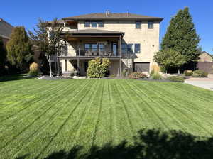 Rear view of house with a balcony and a lawn