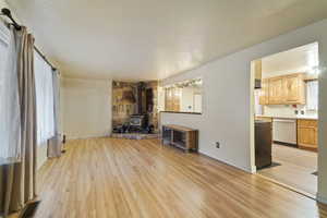 Unfurnished living room with light hardwood / wood-style floors, a textured ceiling, and a wood stove