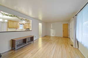 Unfurnished living room featuring an inviting chandelier and light hardwood / wood-style floors