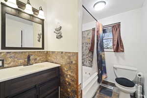 Full bathroom featuring shower / bath combo, vanity, a textured ceiling, and toilet