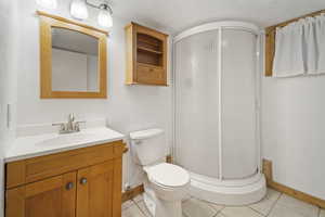 Bathroom with tile patterned flooring, vanity, toilet, and walk in shower