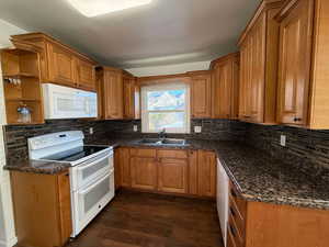 Kitchen featuring dark hardwood / wood-style flooring, sink, white appliances, and backsplash