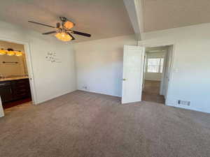 Unfurnished bedroom featuring light colored carpet, a textured ceiling, and ensuite bath