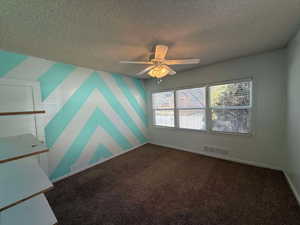 Spare room featuring ceiling fan, carpet flooring, and a textured ceiling