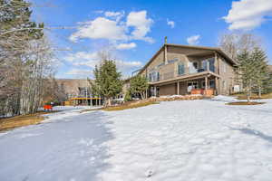 Snow covered rear of property featuring a balcony