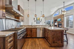 Kitchen featuring sink, a breakfast bar area, kitchen peninsula, stainless steel appliances, and range hood