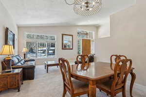 Dining space featuring lofted ceiling, light colored carpet, and a healthy amount of sunlight