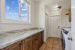 Kitchen featuring washing machine and dryer and light tile patterned flooring