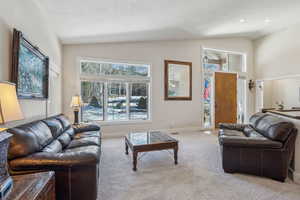 Living room with vaulted ceiling and light carpet