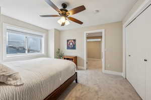 Bedroom with light colored carpet, ceiling fan, and a closet