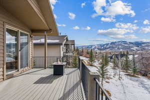 Snow covered deck featuring a mountain view and an outdoor fire pit