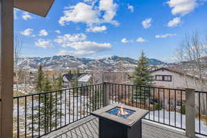 Snow covered back of property featuring an outdoor fire pit and a mountain view