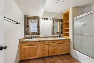 Bathroom with enclosed tub / shower combo, vanity, and tile patterned flooring