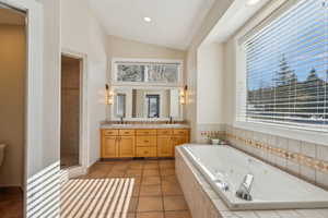 Bathroom featuring vanity, lofted ceiling, tile patterned floors, and separate shower and tub