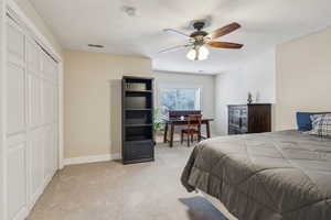 Carpeted bedroom featuring ceiling fan and a closet