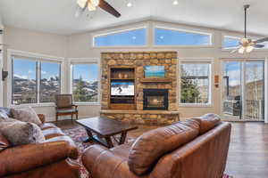 Living room featuring a mountain view, hardwood / wood-style floors, a stone fireplace, and ceiling fan