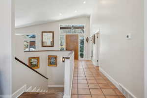 Hallway with vaulted ceiling and light tile patterned flooring