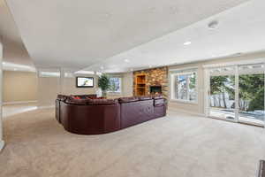 Living room with a stone fireplace, light carpet, and a textured ceiling