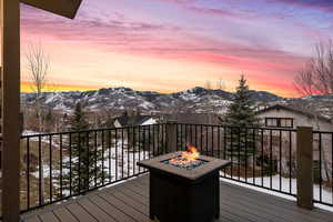 Snow covered deck with a mountain view and an outdoor fire pit