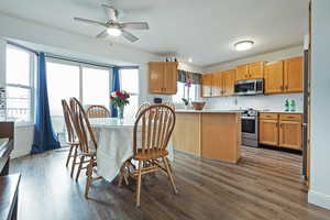 Kitchen with a kitchen island, appliances with stainless steel finishes, a breakfast bar, hardwood / wood-style floors, and ceiling fan