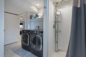 Laundry room featuring light tile patterned flooring and washer and clothes dryer